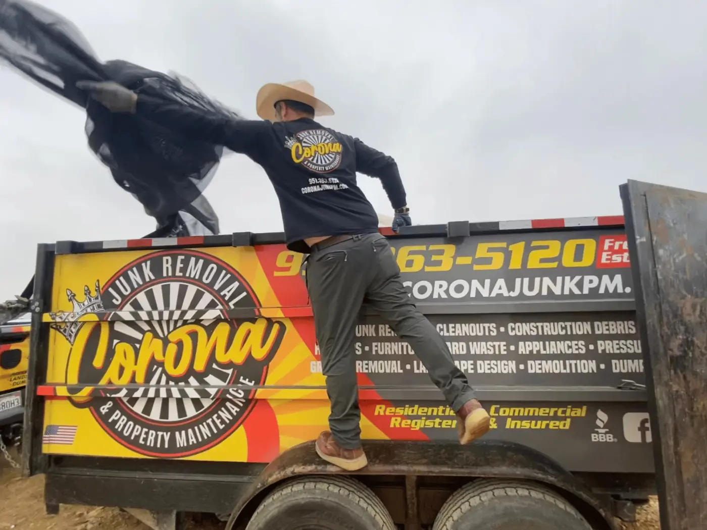 Corona Junk Removal crew loading a branded trailer during a local junk removal job